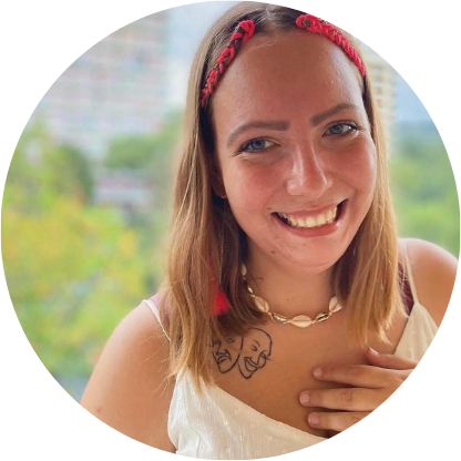 Nie wiem, kto jest na zdjęciu. Kobieta z tatuażem na ramieniu, uśmiecha się, stojąc na tle rozmytego krajobrazu.