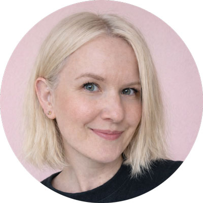 Nie wiem, kto jest na zdjęciu. Uśmiechnięta osoba z krótkimi blond włosami na różowym tle w czarnym swetrze.